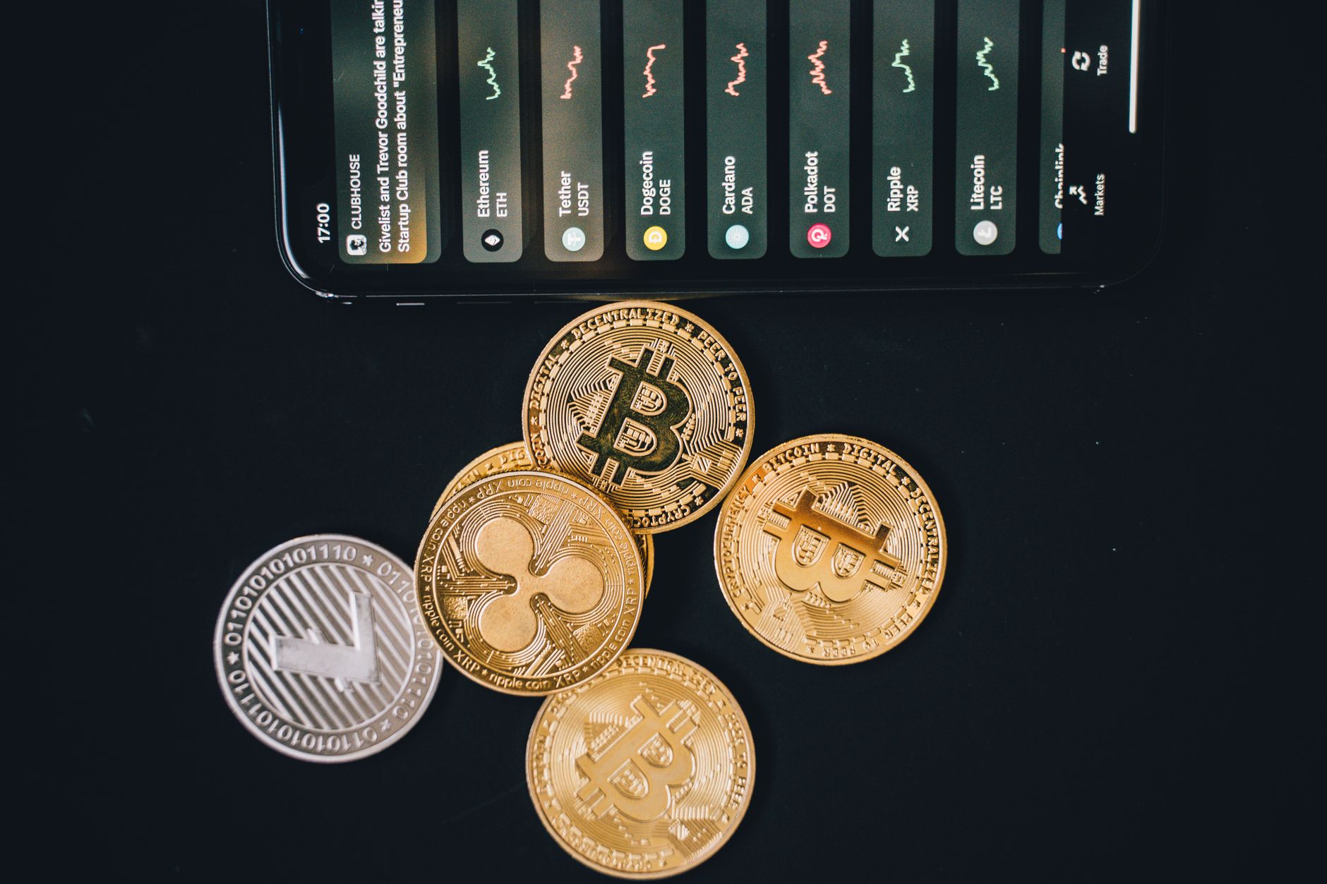 Close-up of various cryptocurrencies and a smartphone showing market trends.