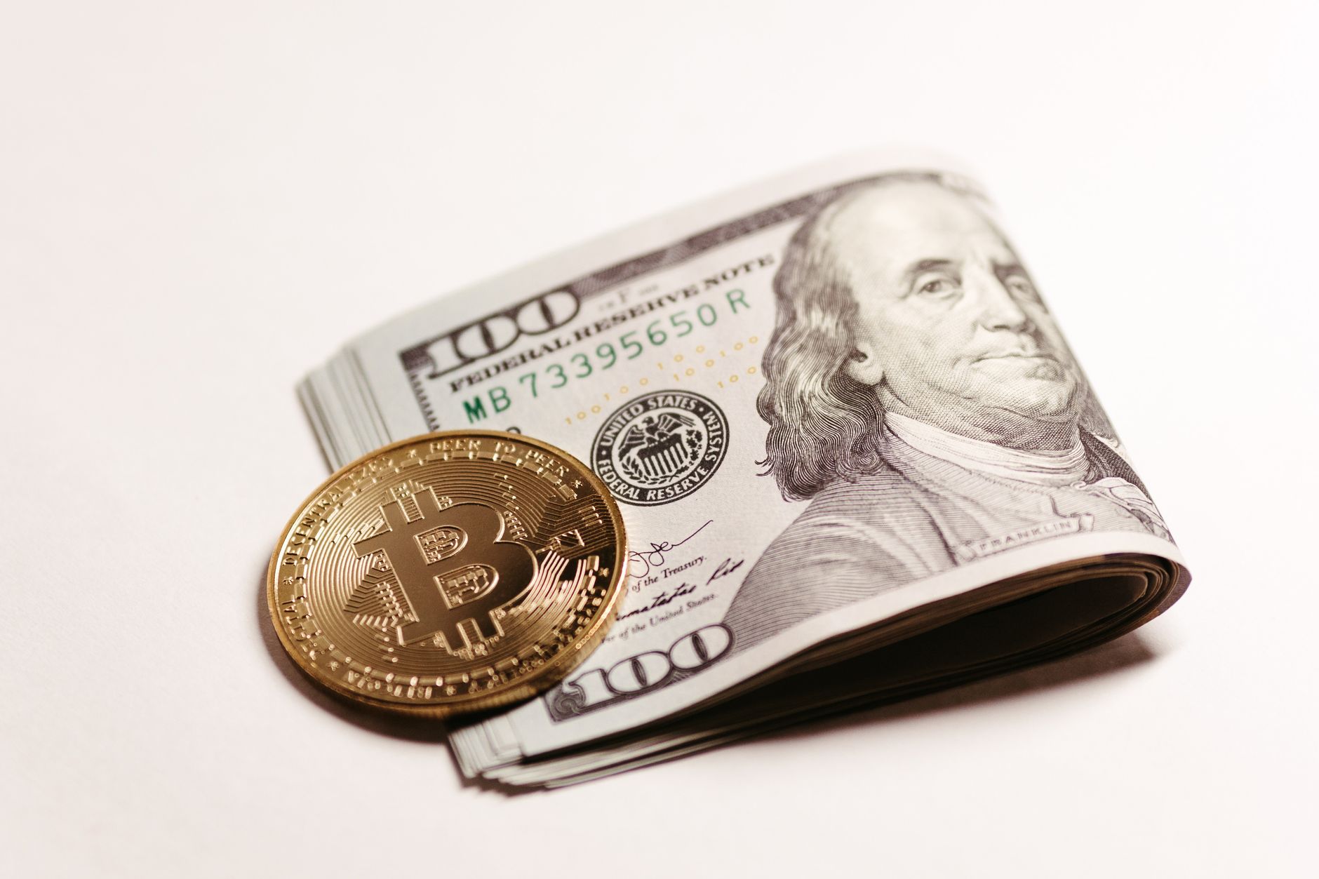 Close-up of a Bitcoin coin on top of US dollar bills symbolizing cryptocurrency and traditional finance.