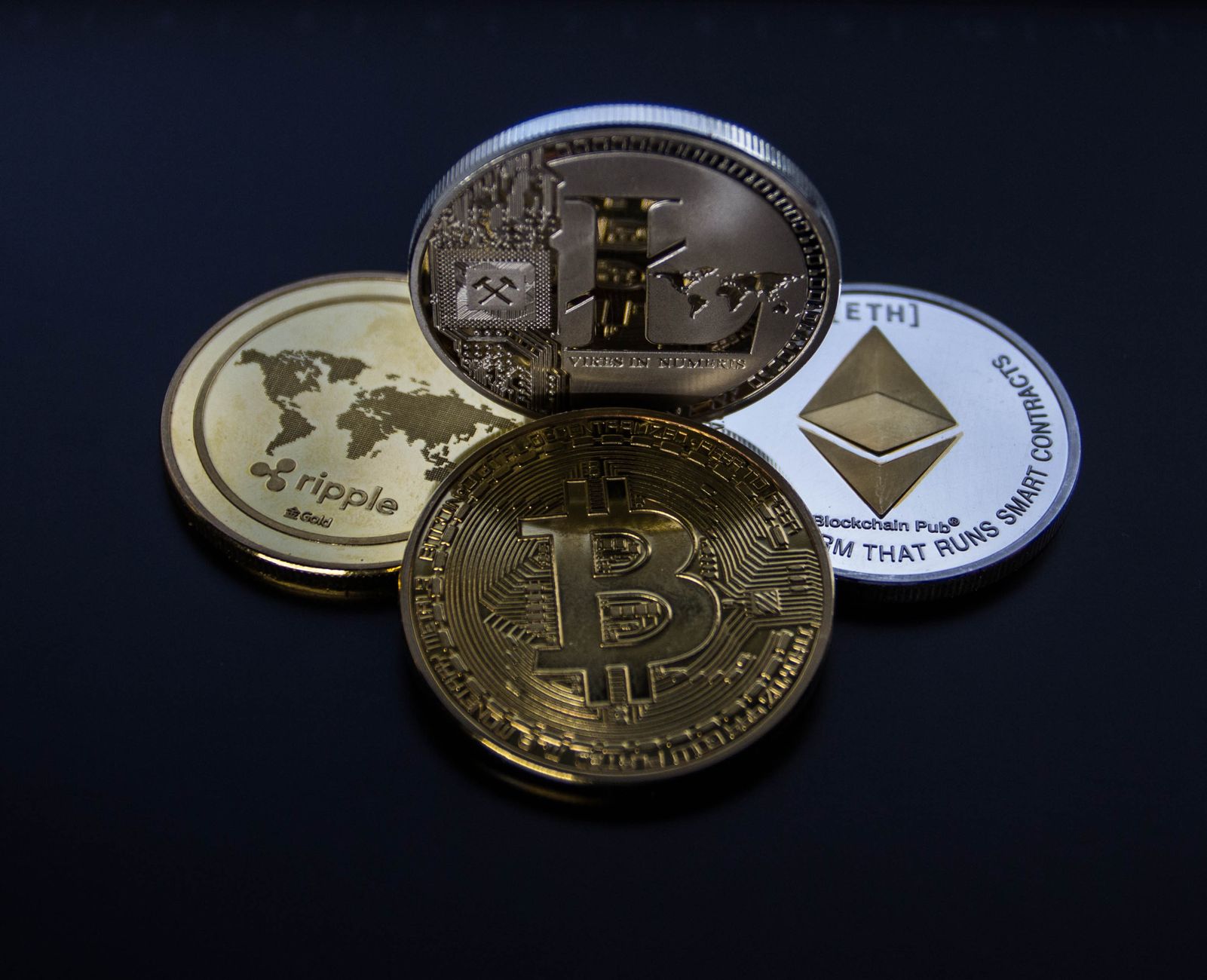 Detailed photo showcasing bitcoin, ethereum, litecoin, and ripple coins representing digital currency.