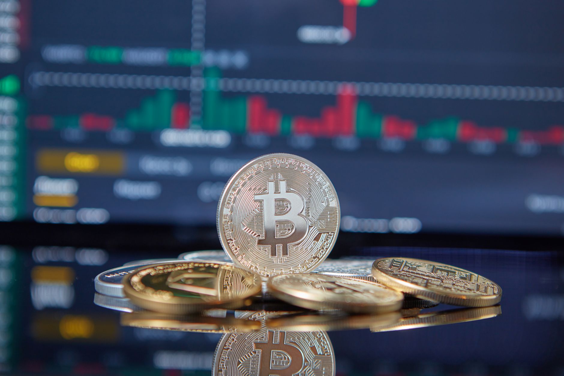 Bitcoin cryptocurrency coins in focus with a blurred stock market chart in the background, representing investment and finance.