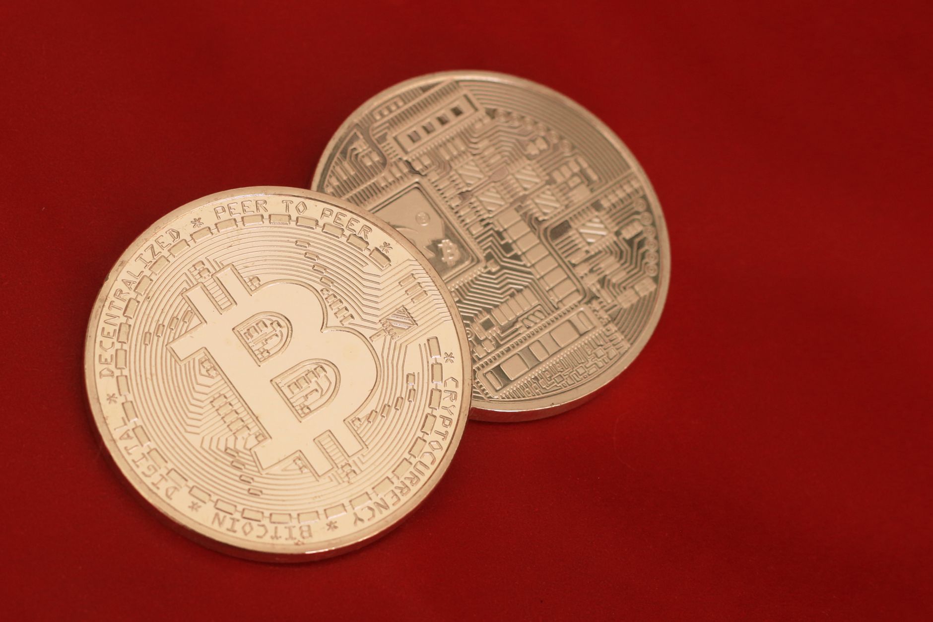 Detailed close-up of two Bitcoin coins on a red background, symbolizing digital currency.