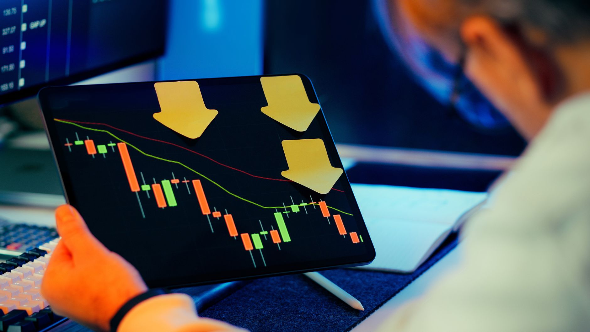 A businessman analyzing a bearish stock market trend on a tablet, indicating financial instability and potential crisis.