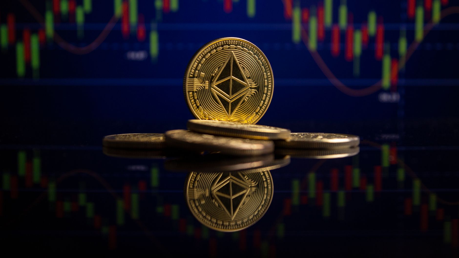 Ethereum coins on reflective surface with stock market chart behind, showcasing cryptocurrency trading.
